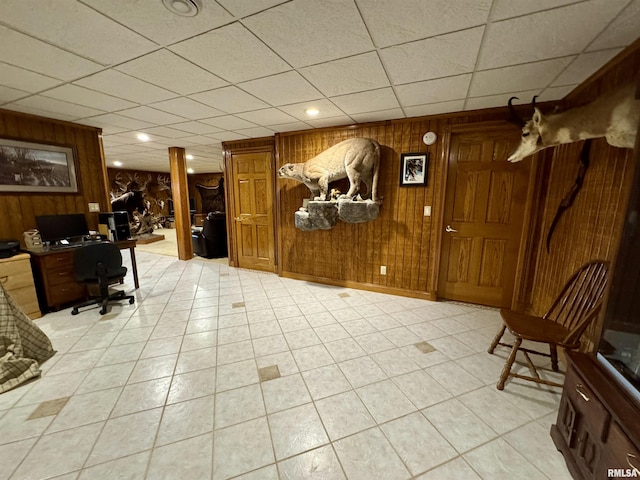 home office with a paneled ceiling and wood walls