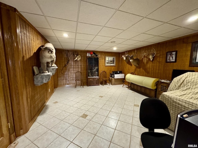 interior space featuring wood walls, light tile patterned floors, and a drop ceiling