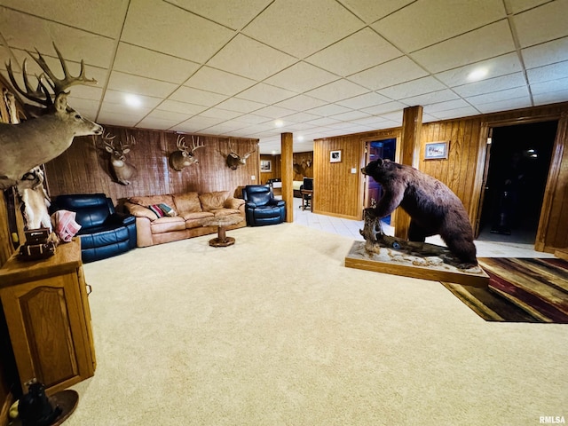 living room featuring a paneled ceiling, wooden walls, and light carpet