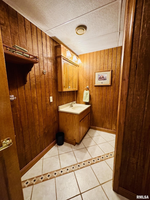 bathroom with tile patterned flooring, sink, a textured ceiling, and wooden walls