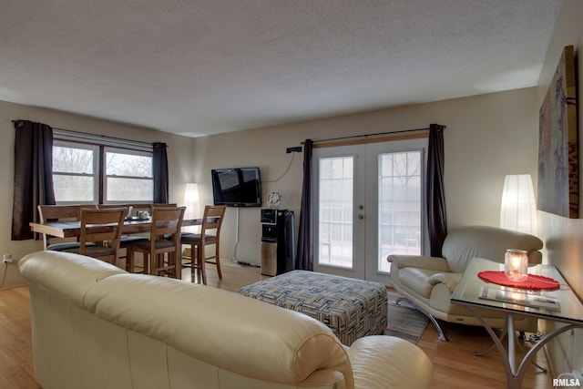 living room featuring french doors, light hardwood / wood-style flooring, and a textured ceiling