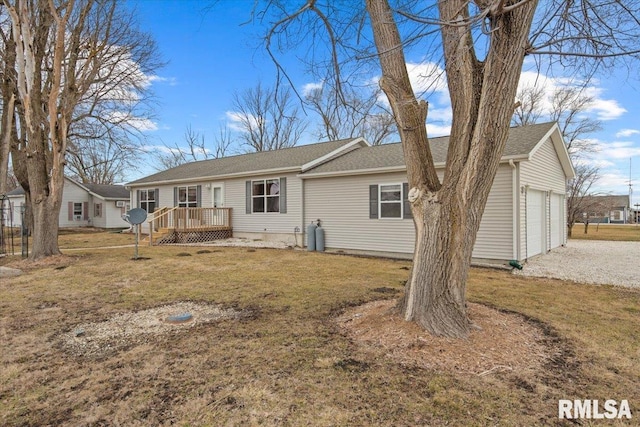 rear view of house featuring a garage, a deck, and a lawn