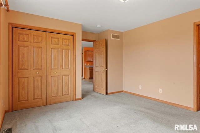 unfurnished bedroom with light colored carpet and a closet