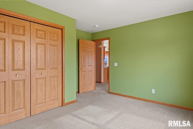 unfurnished bedroom featuring light carpet and a closet