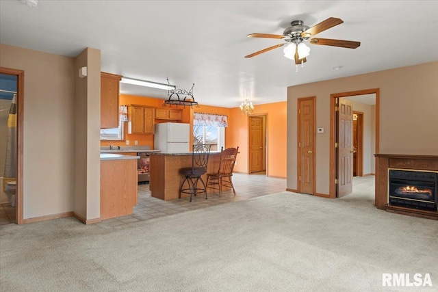 kitchen with a center island, light colored carpet, a kitchen breakfast bar, white fridge, and ceiling fan