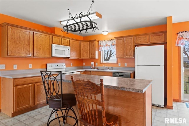 kitchen with rail lighting, sink, a kitchen breakfast bar, a center island, and white appliances