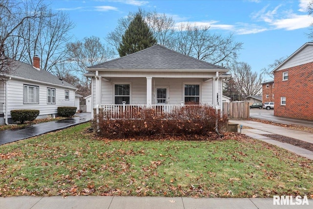 view of front of property with a porch, a shingled roof, and a front yard