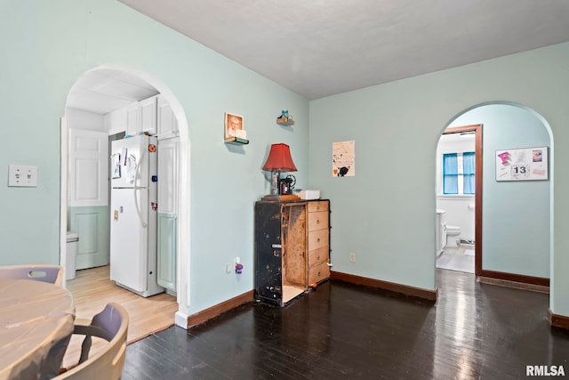 interior space featuring white fridge, hardwood / wood-style floors, and connected bathroom