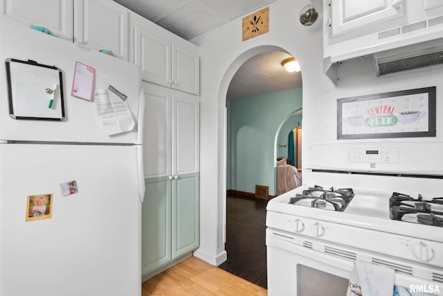 kitchen with white appliances, light hardwood / wood-style flooring, and white cabinets