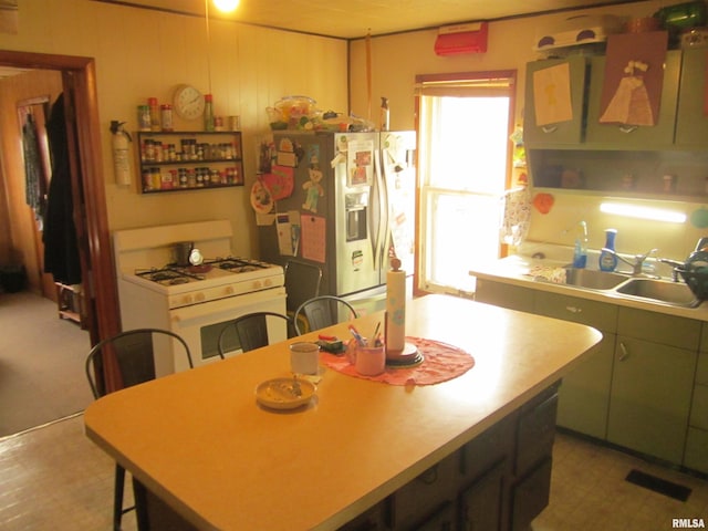 kitchen with a kitchen island, sink, white range with gas stovetop, and refrigerator with ice dispenser