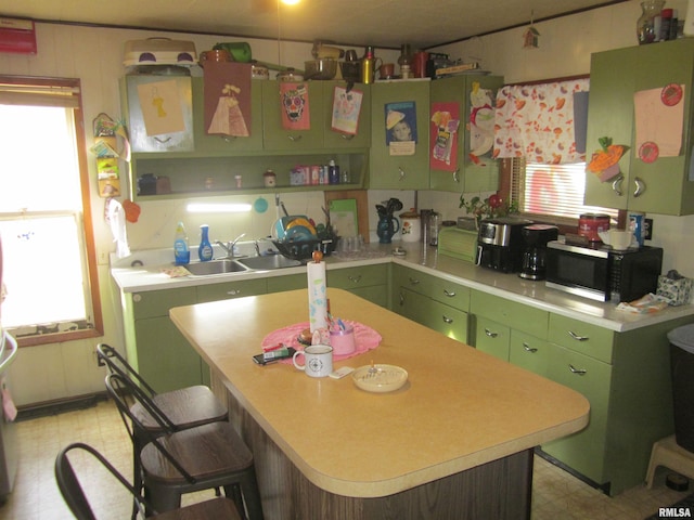 kitchen with green cabinets, a kitchen bar, sink, and a kitchen island