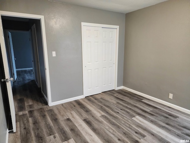 unfurnished bedroom with dark hardwood / wood-style floors and a closet