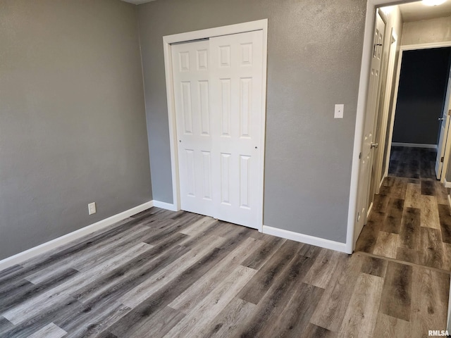 unfurnished bedroom with dark wood-type flooring and a closet