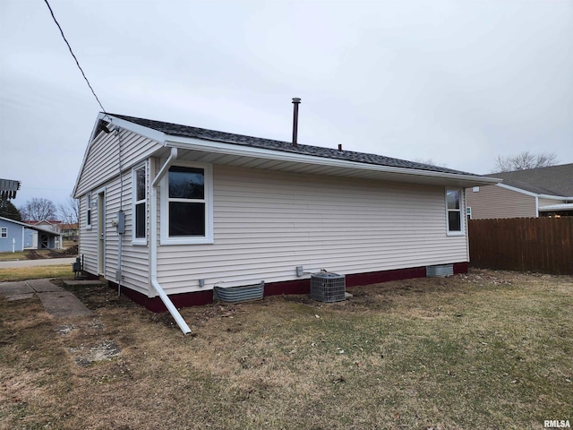 back of property featuring central air condition unit and a lawn