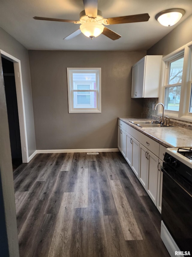 kitchen with sink, white cabinetry, dark hardwood / wood-style floors, ceiling fan, and gas range oven