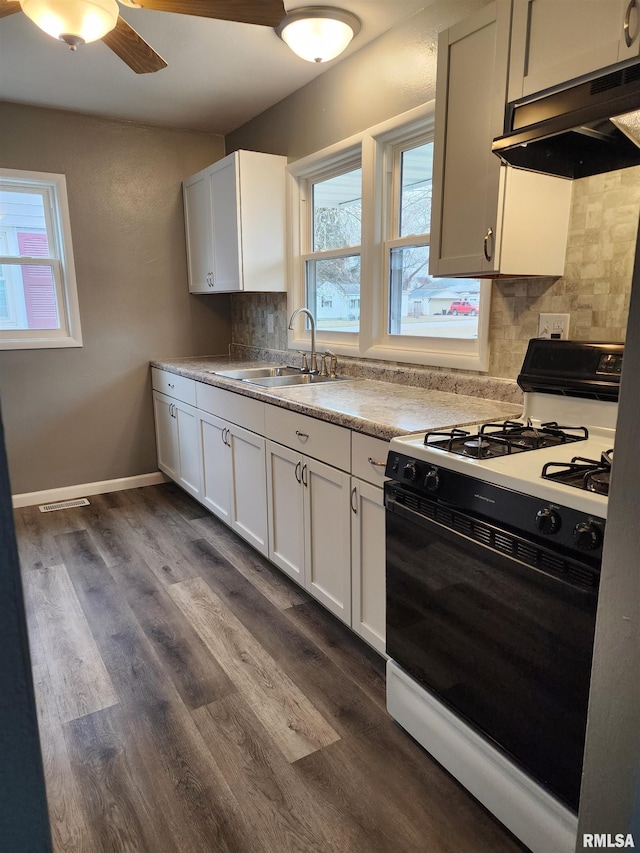 kitchen featuring sink, white cabinetry, ventilation hood, gas range oven, and backsplash