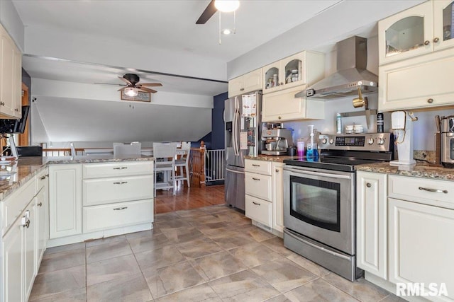 kitchen featuring stainless steel appliances, stone countertops, wall chimney range hood, and ceiling fan