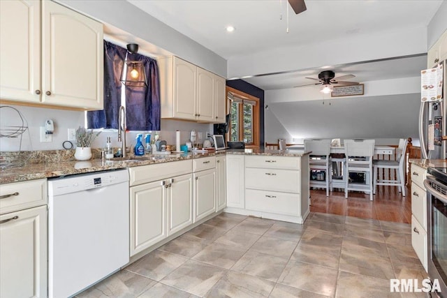 kitchen with appliances with stainless steel finishes, kitchen peninsula, sink, and light stone countertops