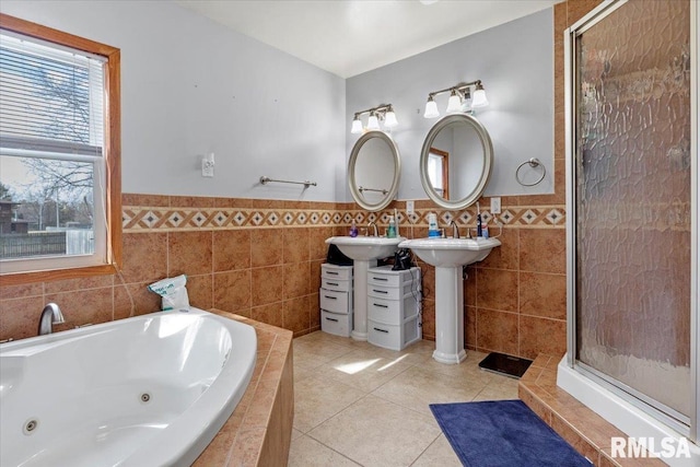 bathroom featuring double sink, tile patterned floors, tiled bath, and tile walls