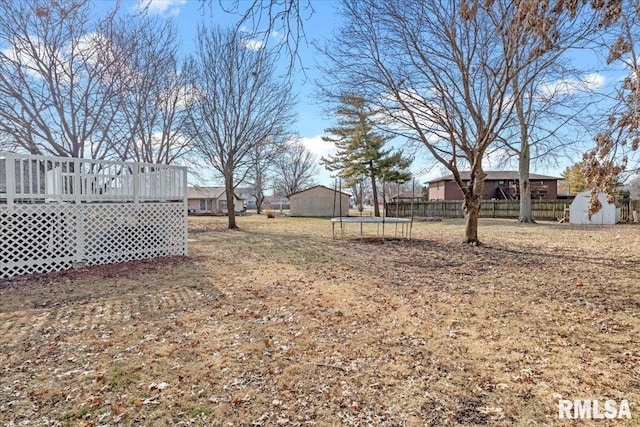 view of yard with a trampoline, a wooden deck, and a shed