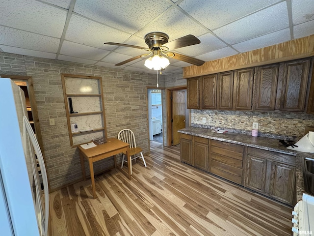 kitchen featuring a paneled ceiling, dark brown cabinets, and light wood-type flooring