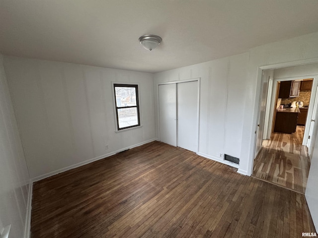 unfurnished bedroom with dark wood-type flooring and a closet