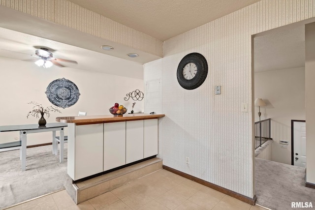 kitchen with white cabinetry, ceiling fan, kitchen peninsula, light carpet, and a textured ceiling