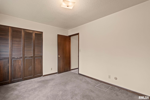 unfurnished bedroom featuring light colored carpet, a closet, and a textured ceiling