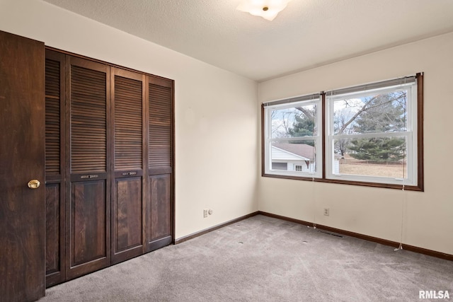 unfurnished bedroom with light colored carpet, a textured ceiling, and a closet