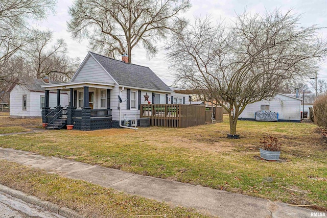 bungalow with central AC unit, covered porch, and a front lawn