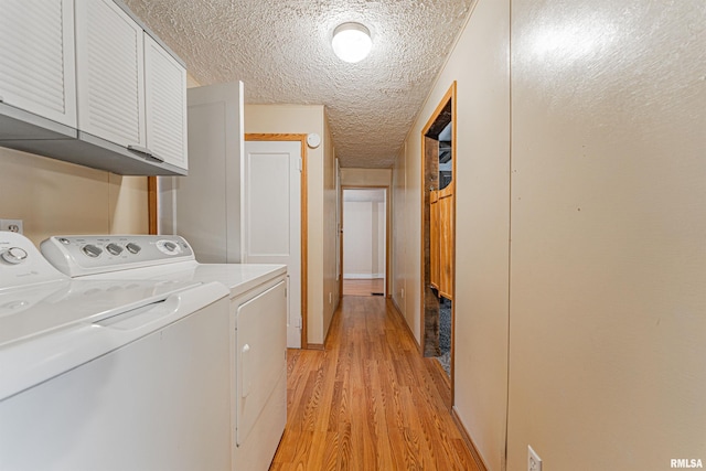 washroom featuring cabinets, washer and clothes dryer, light hardwood / wood-style floors, and a textured ceiling