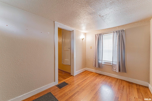 spare room with light hardwood / wood-style flooring and a textured ceiling