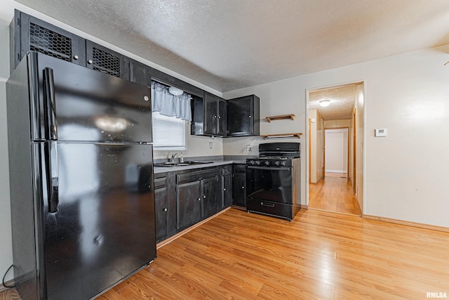 kitchen featuring sink, light hardwood / wood-style flooring, a textured ceiling, and black appliances