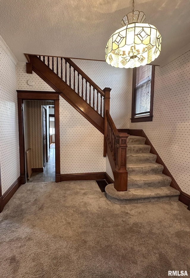 stairs with carpet floors, a chandelier, and a textured ceiling