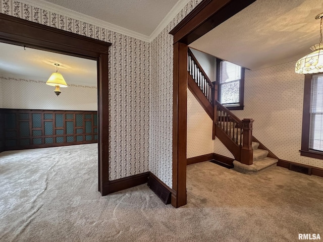 stairway with ornamental molding, carpet, and a textured ceiling