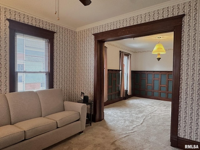 carpeted living room with ornamental molding and ceiling fan