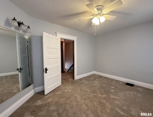 unfurnished bedroom featuring ceiling fan, a textured ceiling, and dark colored carpet