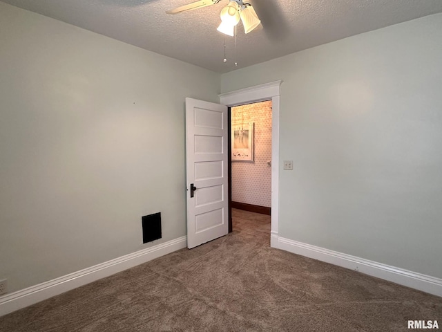 empty room with ceiling fan, a textured ceiling, and dark colored carpet