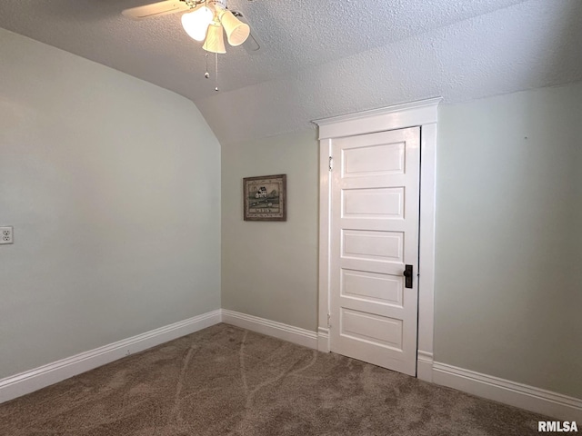 carpeted spare room with ceiling fan, vaulted ceiling, and a textured ceiling