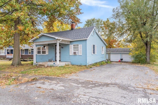 bungalow-style home with a garage, an outdoor structure, and covered porch