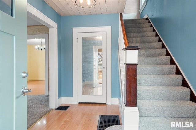 stairway with a notable chandelier, wooden ceiling, and hardwood / wood-style floors