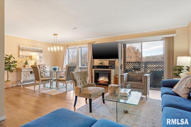 living room featuring ornamental molding, a healthy amount of sunlight, light hardwood / wood-style flooring, and a textured ceiling