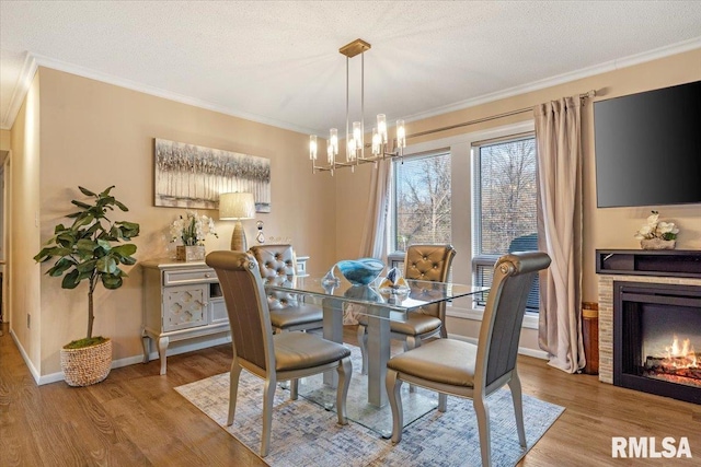 dining room featuring an inviting chandelier, ornamental molding, light hardwood / wood-style floors, and a textured ceiling