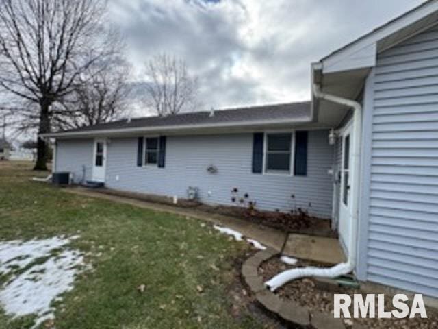 rear view of property with central AC unit and a yard