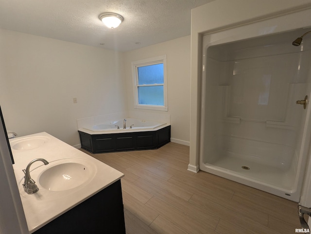 bathroom with vanity, wood-type flooring, plus walk in shower, and a textured ceiling