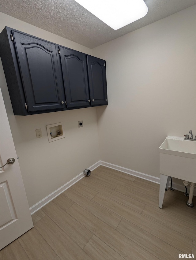 laundry room featuring light hardwood / wood-style flooring, hookup for a washing machine, cabinets, a textured ceiling, and hookup for an electric dryer