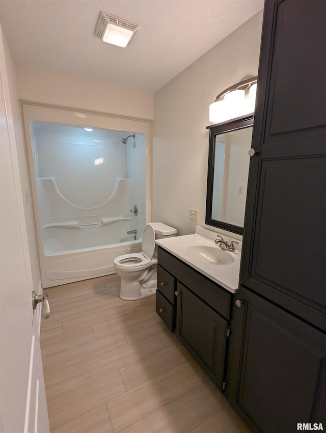 full bathroom featuring hardwood / wood-style floors, vanity, shower / bathing tub combination, a textured ceiling, and toilet