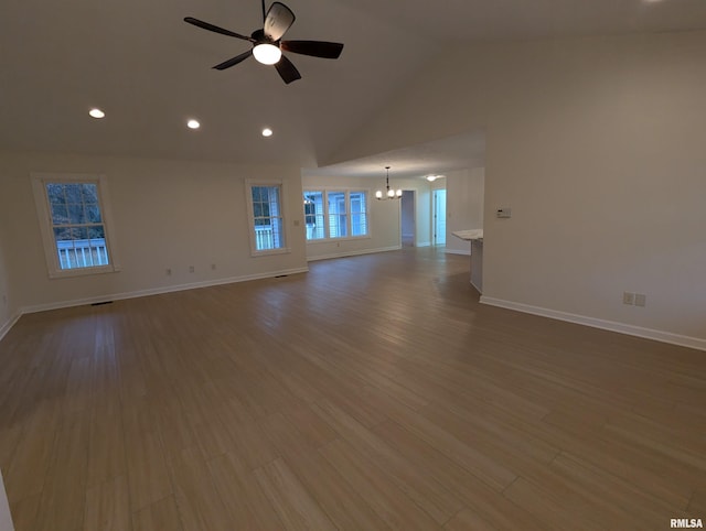 unfurnished living room featuring hardwood / wood-style flooring, vaulted ceiling, and ceiling fan with notable chandelier