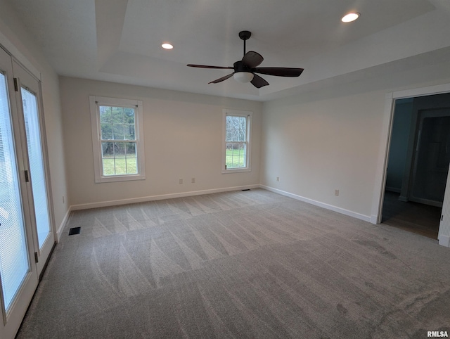 carpeted spare room featuring ceiling fan and a tray ceiling