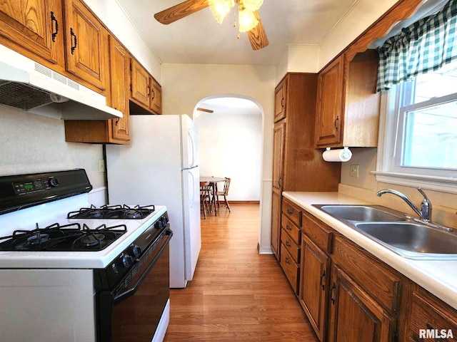 kitchen with white gas range, sink, ceiling fan, and light wood-type flooring